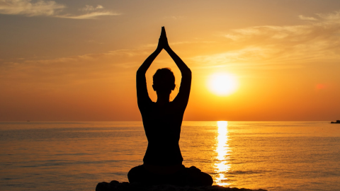 Woman enjoying yoga on the beach at sunset